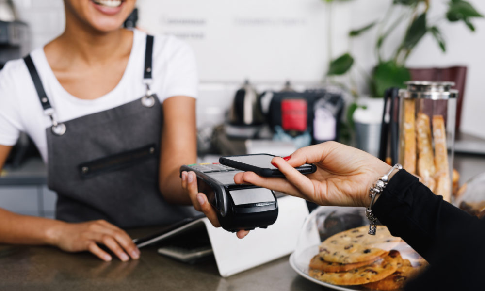 Customer making a contactless mobile payment at a retail counter using a POS terminal, supporting seamless digital transactions