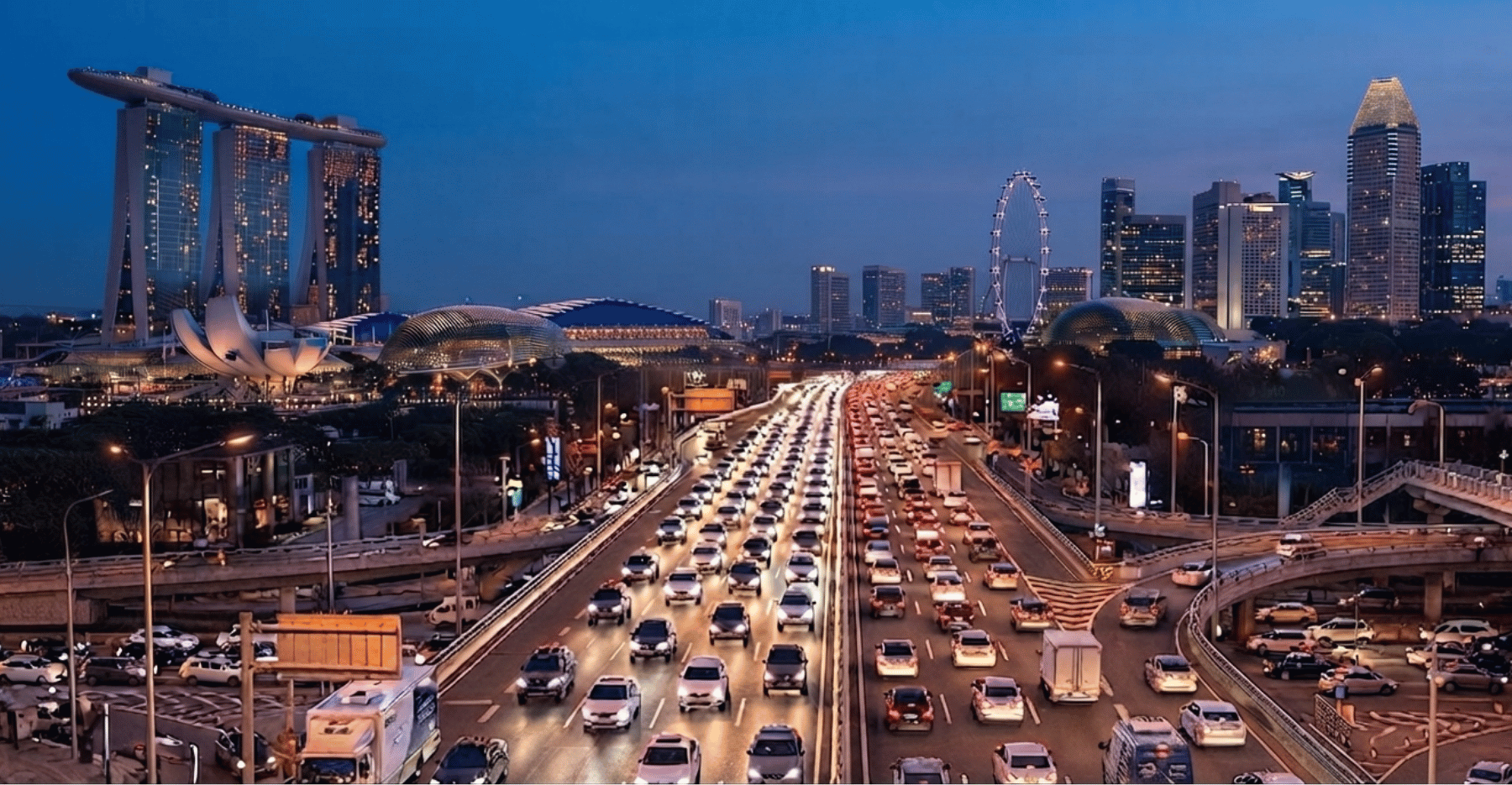 Evening view of Singapore's Marina Bay Sands, Flyer, and Esplanade with heavy highway traffic.