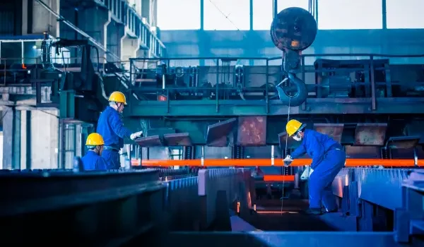 Workers operating machinery in a manufacturing facility, representing industrial production, factory operations, and engineering processes