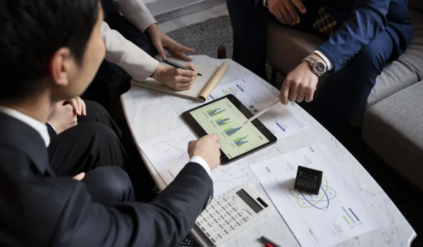 Business professionals reviewing financial data on a tablet with charts and reports during a strategy meeting in a modern office